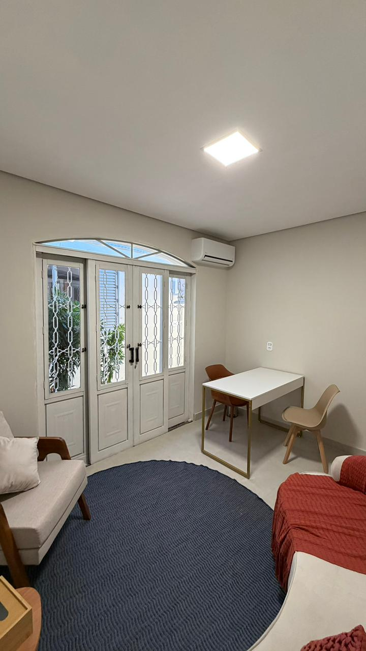 Sala 6 com sofá, mesa de trabalho e porta-vitrô com iluminação natural